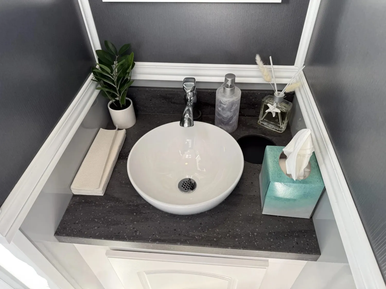 Climate-controlled portable restroom interior with a porcelain sink and refined finishes in Dana Point.