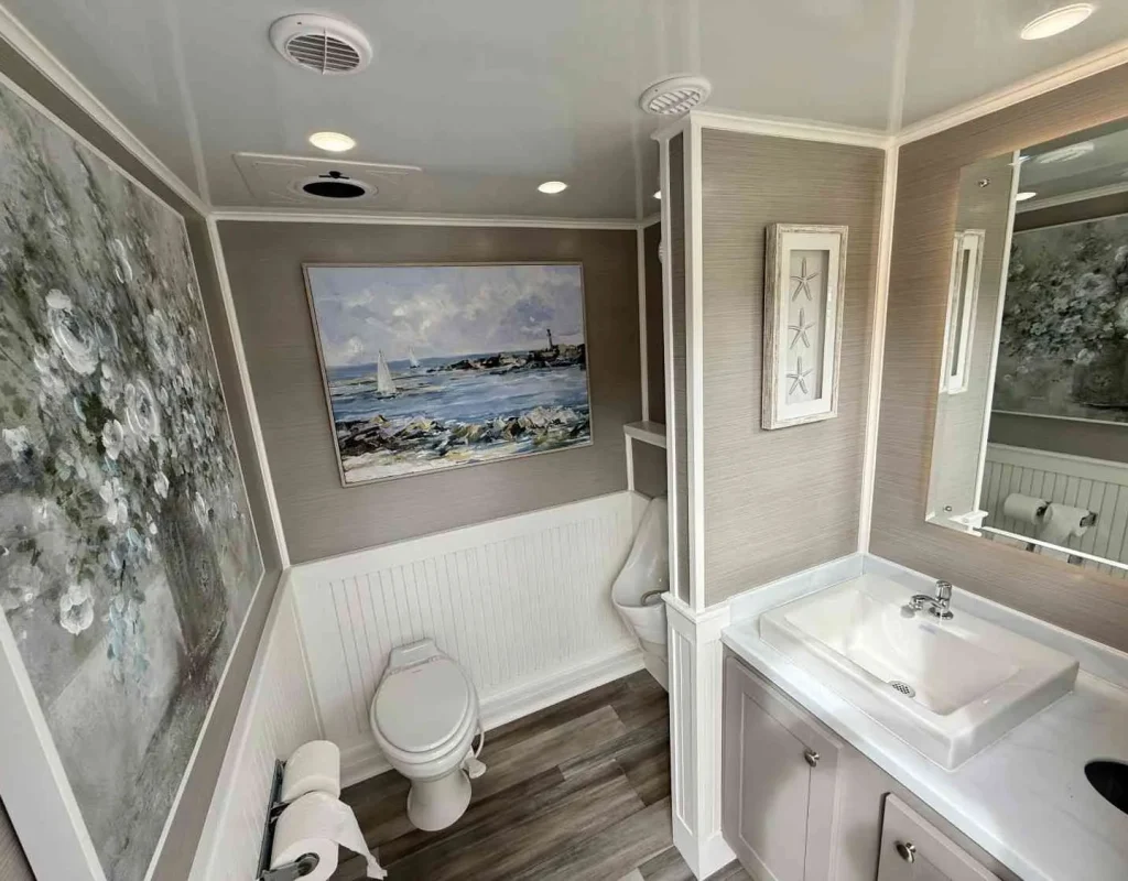Luxury restroom trailer vanity with running-water sink, mirror, lighting, and finished interior details.